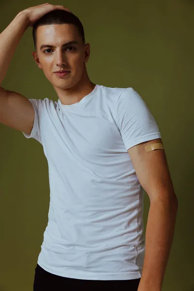 Knappe man in wit t-shirt pleister op zijn arm covid vaccinpaspoort — Stockfoto