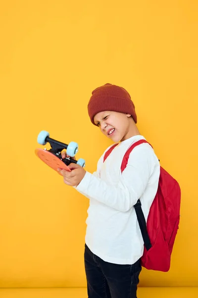 Glada liten unge med röd ryggsäck röd skateboard isolerad bakgrund — Stockfoto