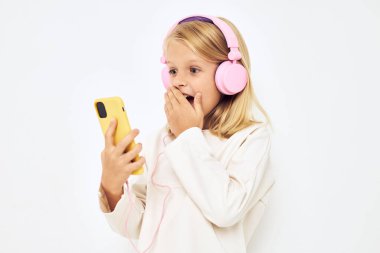 Sarı saçlı bir kız telefona şaşkın şaşkın bakar.