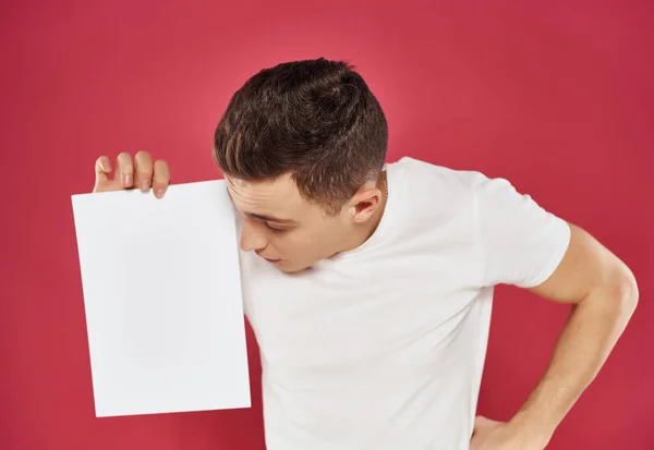 Man in een wit t-shirt met een vel papier Copy Space — Stockfoto