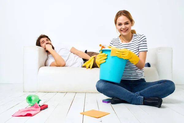 Hombre y mujer cerca del sofá detergente trapos esponjas fondo claro — Foto de Stock