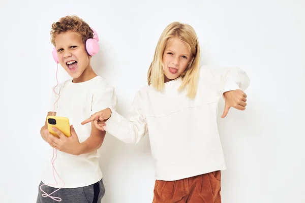 Dvě předškolní děti chlapec a dívka při pohledu na telefon pózovat světlo pozadí — Stock fotografie