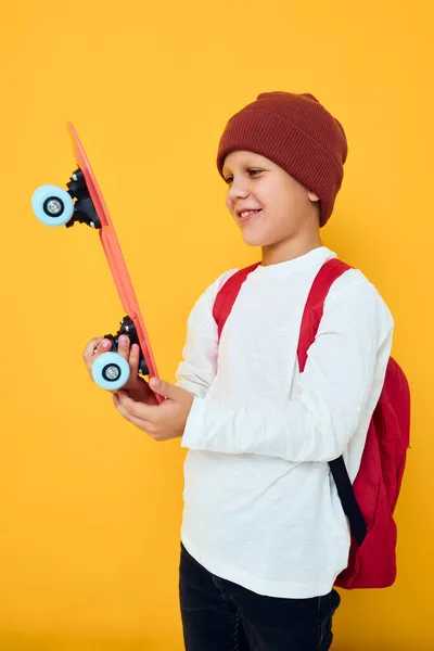 Glücklicher Schuljunge mit rotem Rucksack rotes Skateboard — Stockfoto