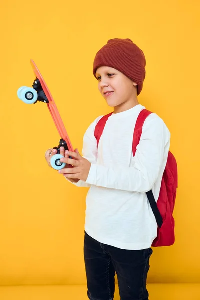 Porträt süßer Jungen mit rotem Rucksack und rotem Skateboard — Stockfoto