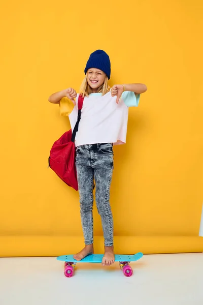 かわいい女の子の写真が赤いバックパックでスケートボードに乗って孤立した背景 — ストック写真