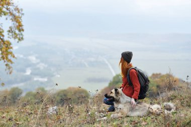 Sırt çantalı, köpekli bir kadın yürüyüşçü.