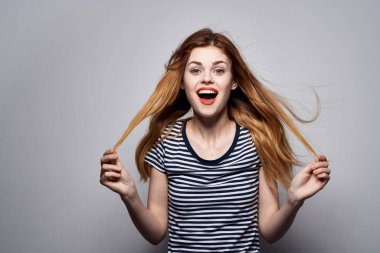 Komik model stüdyosu pozu veren, elinde saç makyajı olan neşeli bir kadın.