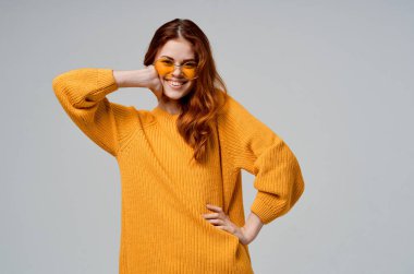 Sarı süveterli, gözlüklü, hafif arka planlı güzel bir kadın.