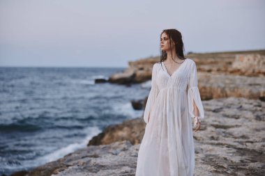 Kadın kayaların üzerinde duran mesafeye bakıyor okyanus manzarası seyahati