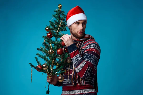 Noel Baba şapkalı neşeli adam bayramın mavi arka planını elinde tutuyor. — Stok fotoğraf