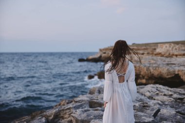 Güzel bir kadın adada volkanik kaya oluşumlarında yürür.