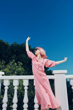 Güneş gözlüğü takan pembe saçlı çekici kadın rahatlama konsepti takıyor.