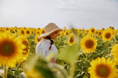 İki örgülü kadın, yaz zamanı ayçiçeği tarlasına bakıyor.
