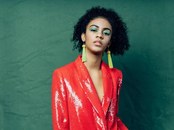 Hermosa mujer en una chaqueta roja joyería maquillaje brillante fondo verde — Foto de Stock