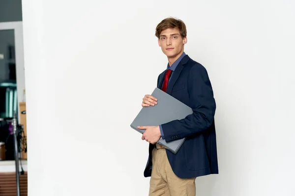 Een man in een blauwe jas en broek en met documenten op een lichte achtergrond — Stockfoto