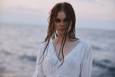 Deniz kıyısında beyaz elbiseli bir kadın gezgin.