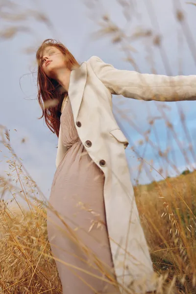 Mooie vrouw jas buiten lopen eindeloos veld — Stockfoto