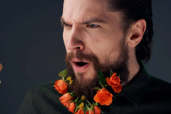 Красивый мужчина с цветами в бороде на темном фоне рубашки — стоковое фото