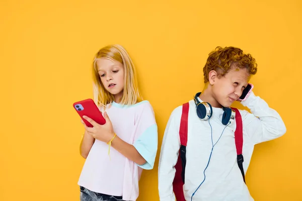 Zwei Kinder Jungen und Mädchen, die auf das Telefon Unterhaltung Kommunikation gelben Hintergrund — Stockfoto