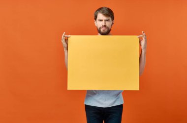 Sarı pankart taşıyan sakallı adam turuncu arka plan