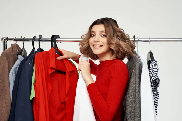 Csinos nő mellett ruhák divat szórakoztató kiskereskedelmi fény háttér — Stock Fotó