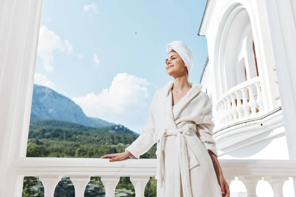 Привлекательная молодая женщина, стоящая на балконе и смотрящая на горный отдых в горах летом без изменений — стоковое фото
