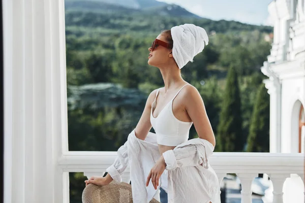 Mujer en gafas de sol con una toalla en la cabeza cerca del balcón — Foto de Stock