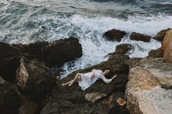 Güzel gelin, ıssız bir yerde vahşi kayalık bir sahilde beyaz elbiseli doğa manzaralı. — Stok fotoğraf