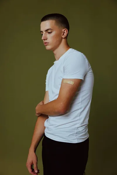 Mladý muž v bílém tričku se sádrou na pažním očkovacím pasu covid-19 — Stock fotografie