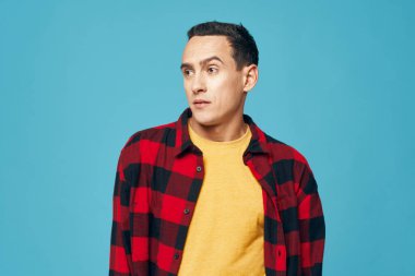 Ekose gömlekli bir adam. Duyguları normal. Mavi arka plan giyiyor.