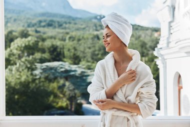 Güzel bir kadın balkonda durmuş dağlara bakıyor yazın dağlarda değişmeden tatil yapıyor.