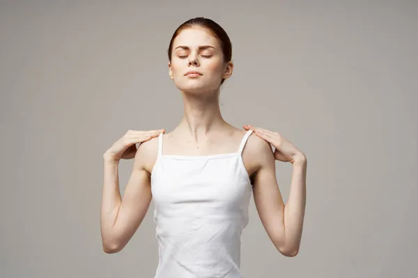 Γυναίκα σε λευκό t-shirt κρατώντας το λαιμό προβλήματα υγείας κοινή θεραπεία στούντιο — Φωτογραφία Αρχείου