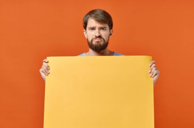 Sarı pankart taşıyan sakallı adam turuncu arka plan