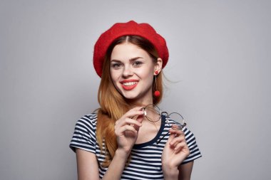 Gözlüklü neşeli bir kadın çekici bir poz veriyor. Kırmızı küpeler takıyor.