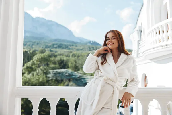 Pelo largo de mujer en un albornoz blanco alojado en el balcón en un hotel Mañana soleada perfecta — Foto de Stock