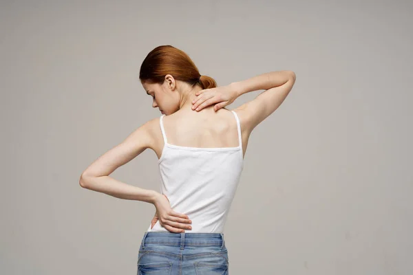 Nő fehér pólóban hátfájás egészségügyi problémák csontritkulás stúdió kezelés — Stock Fotó