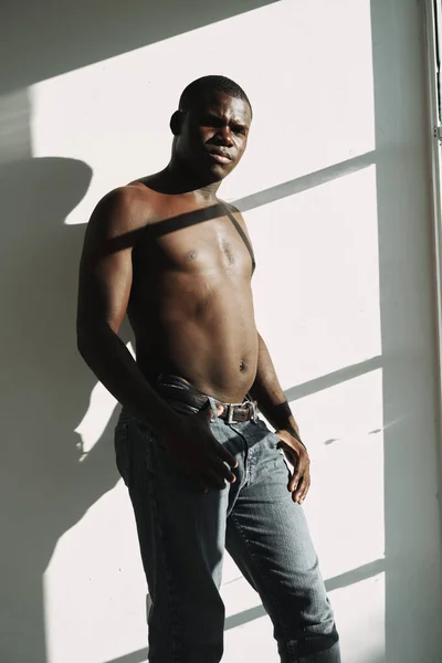 Hombre africano en jeans torso desnudo cerca de la ventana —  Fotos de Stock