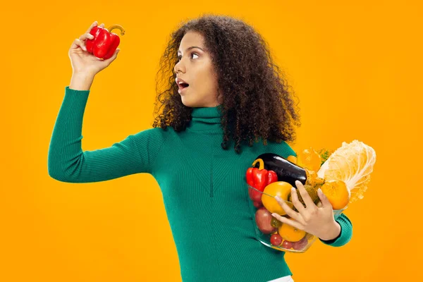 手握卷发蔬菜的妇女健康食品黄背景 — 图库照片