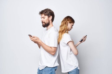 Beyaz tişörtlü, ellerinde telefonlar olan genç bir çift.