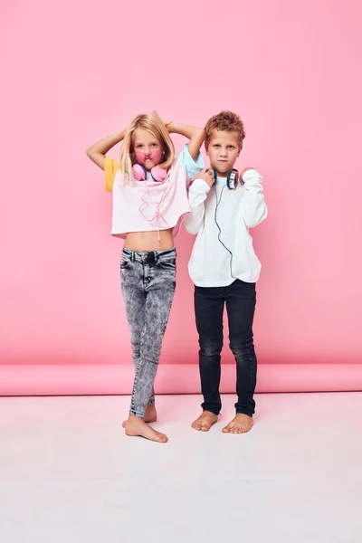 Lindo sonriendo niños usando auriculares posando rosa color de fondo —  Fotos de Stock