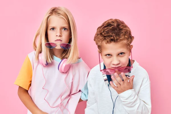 Adorabile bambini in occhiali da sole divertirsi con gli amici sfondo di colore rosa — Foto Stock