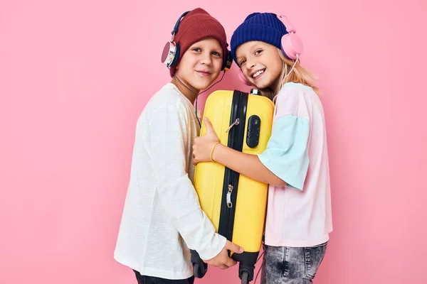Retrato de una niña y un niño elegante ropa maleta auriculares concepto de estilo de vida de la infancia —  Fotos de Stock