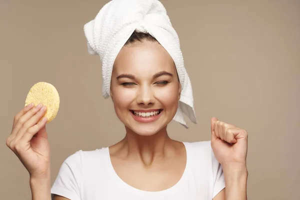 Wanita dengan handuk di kepalanya kosmetik kulit bersih di tangan spons — Stok Foto