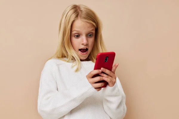 Емоційна дівчина червоний телефон в руці на бежевому фоні — стокове фото
