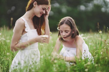 Anne ve kızı tarlada çiçek topluyor.