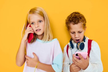 Okul çantalı okul çocukları telefon şakaları sarı arka plan