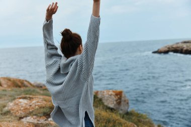 Güzel kadın doğa kıyı manzarasını sallar. Okyanus değişmez.