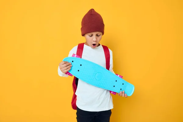 白いセーターの陽気な小さな子供スケートボードエンターテイメント黄色の背景 — ストック写真