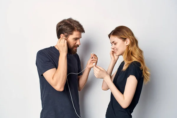 快乐的年轻夫妇，手持手机，头戴耳机，背景浅薄 — 图库照片
