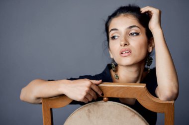 Güzel bir kadın, siyah elbiseli bir hayat stüdyosunda takı takıyor.